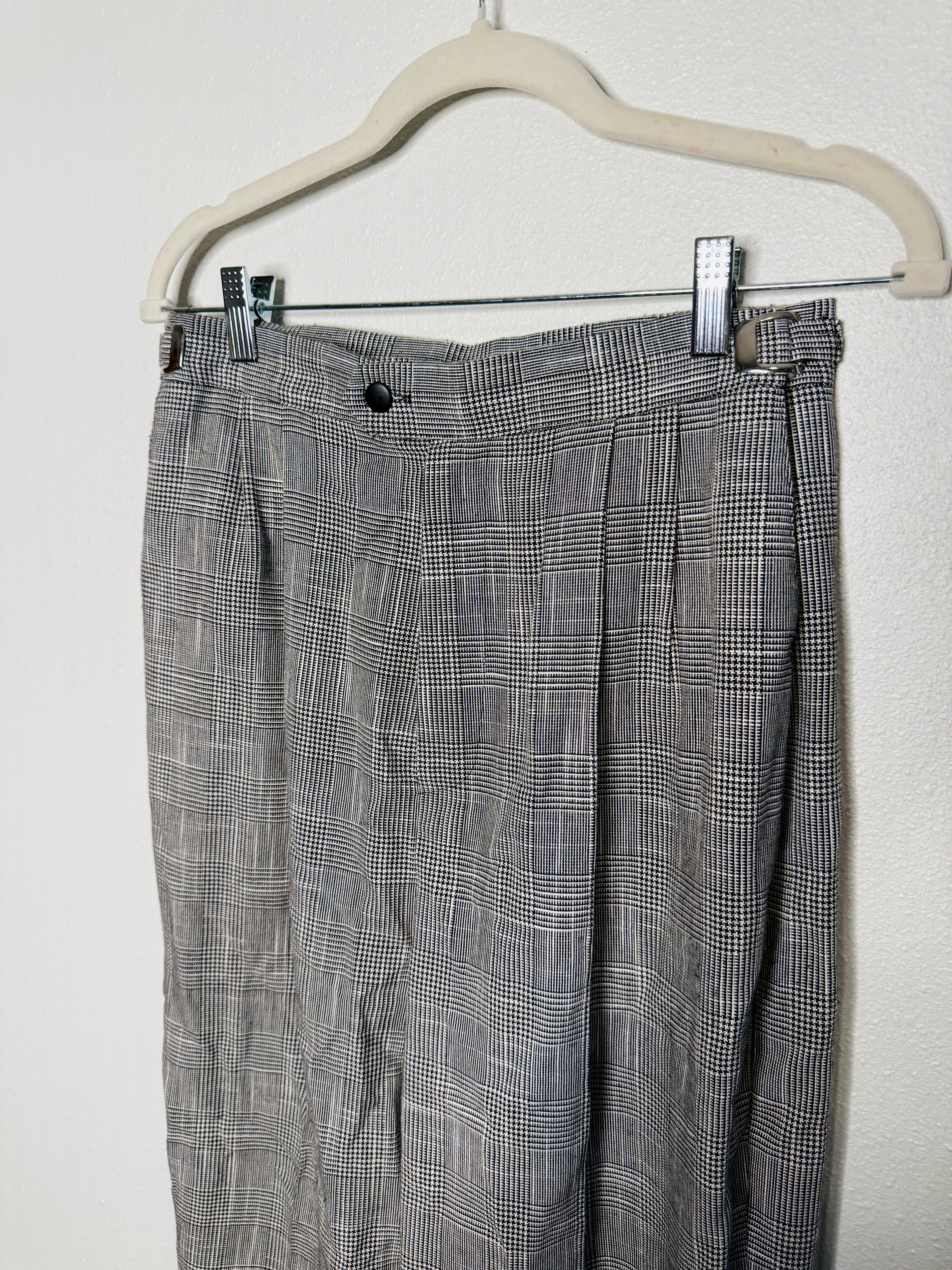 Plaid pants hanging on a white hanger against a white background