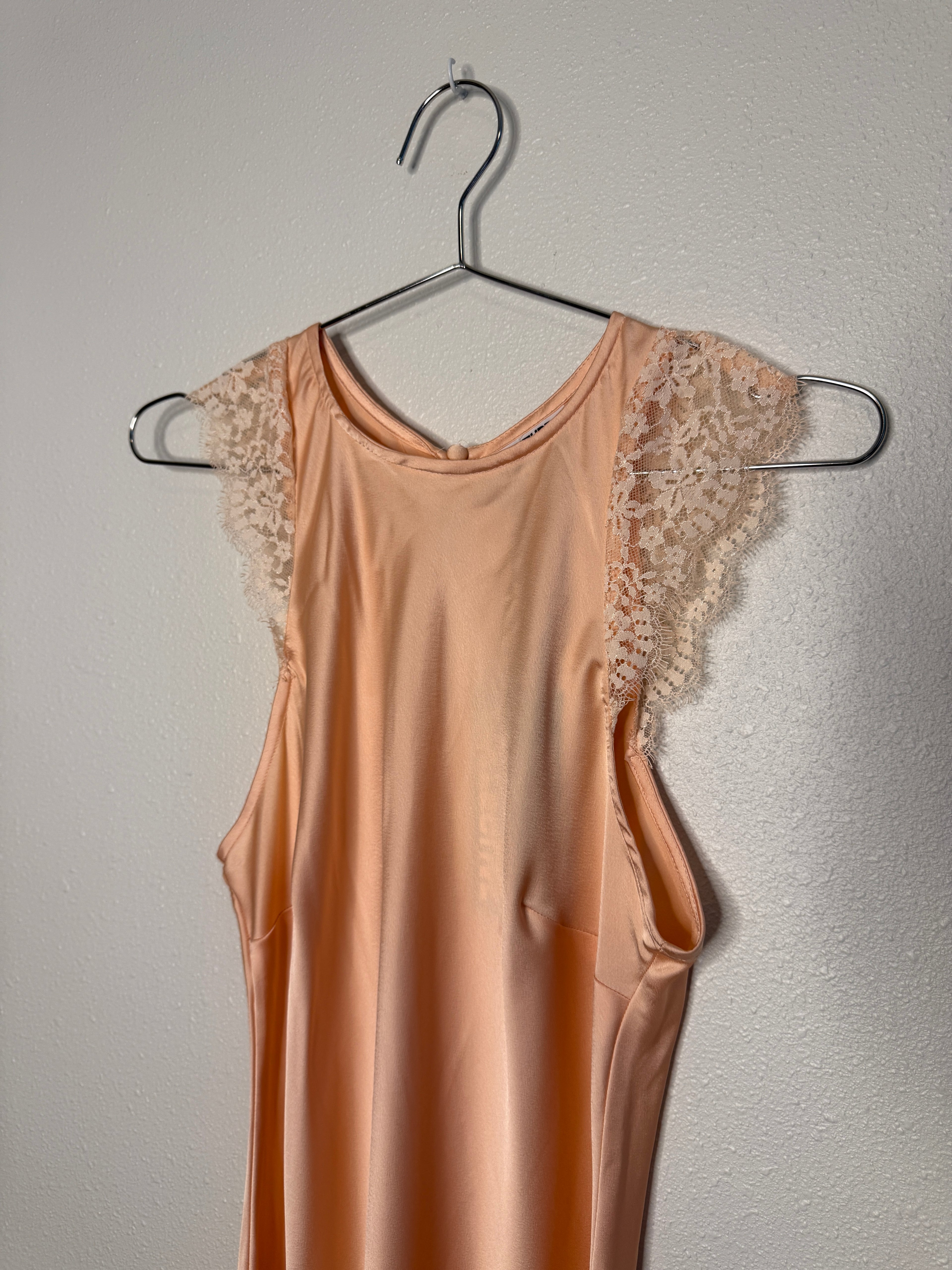 Pink dress with lace details on a hanger against a gray background