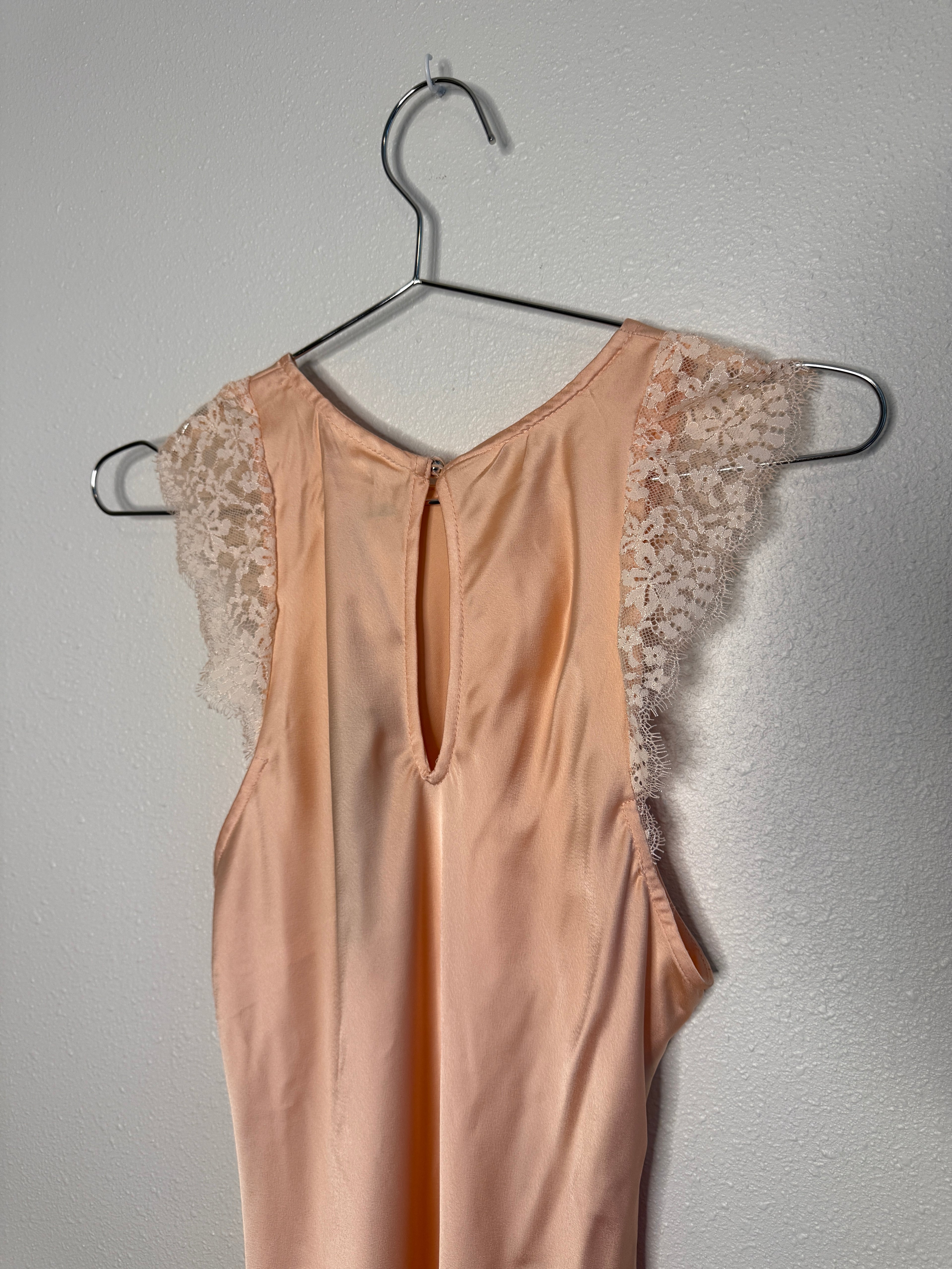 Pink lace dress on a hanger against a gray background