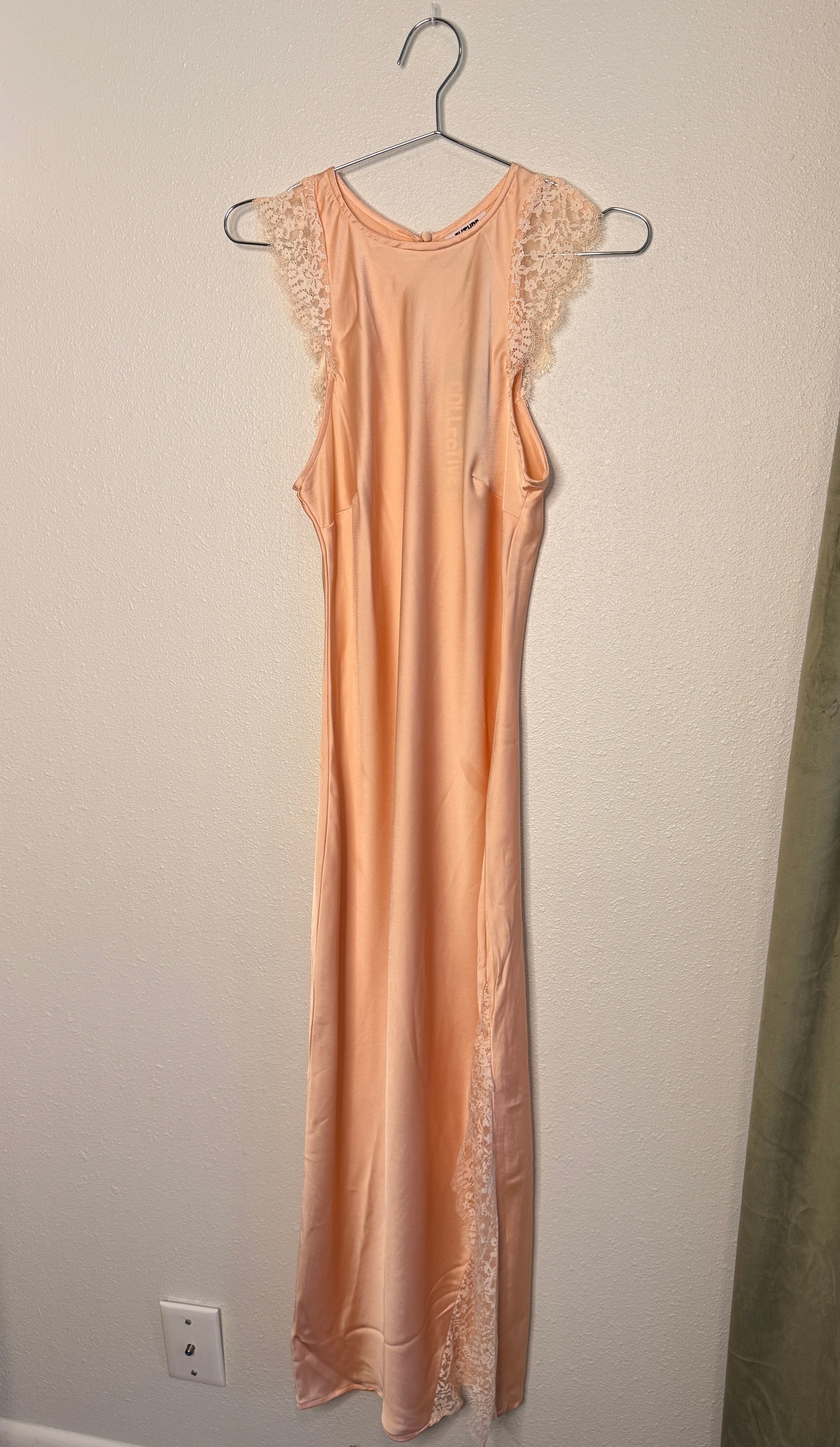 Lace dress on a hanger against a plain wall