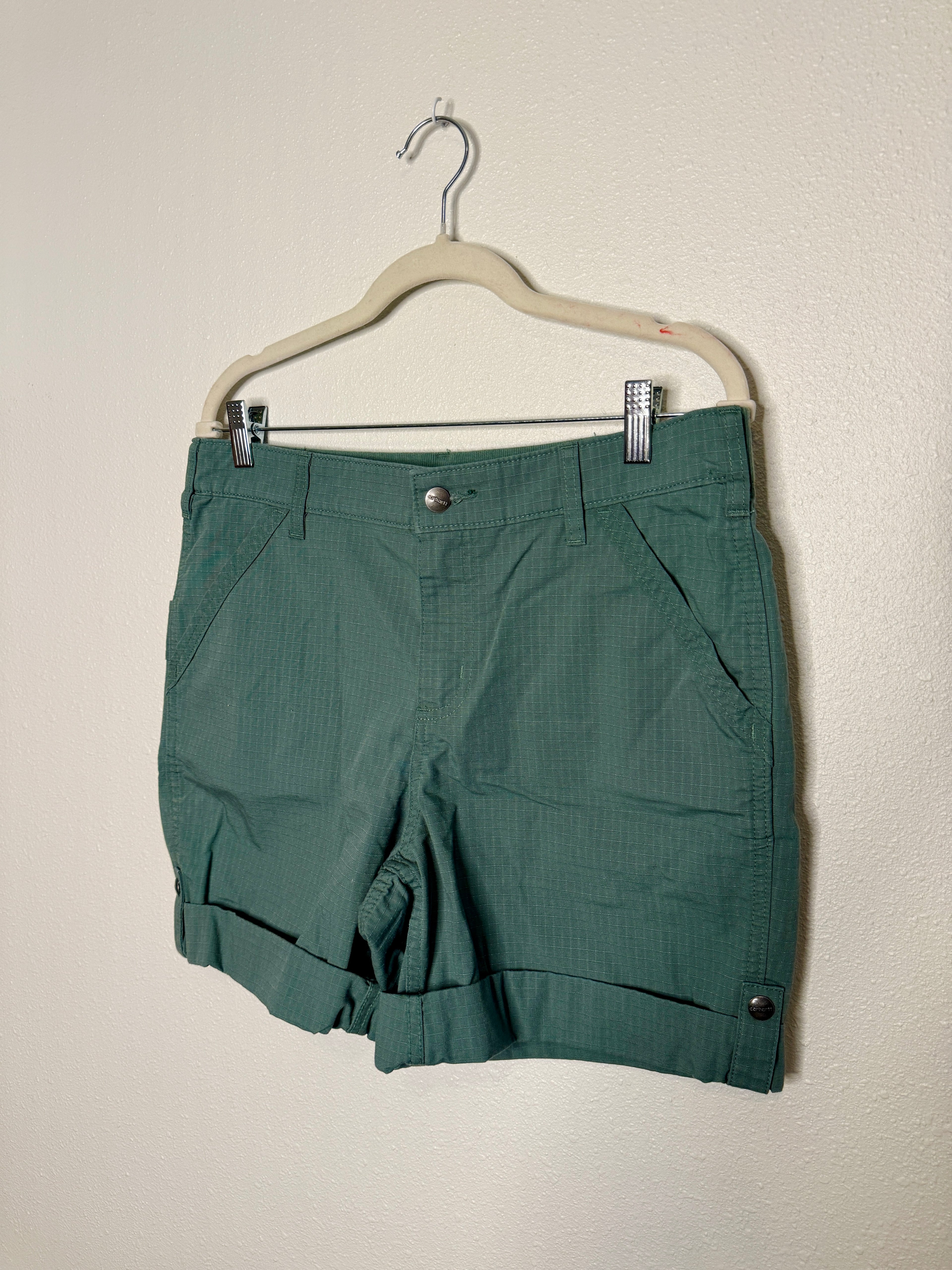 Green shorts on a hanger against a beige background