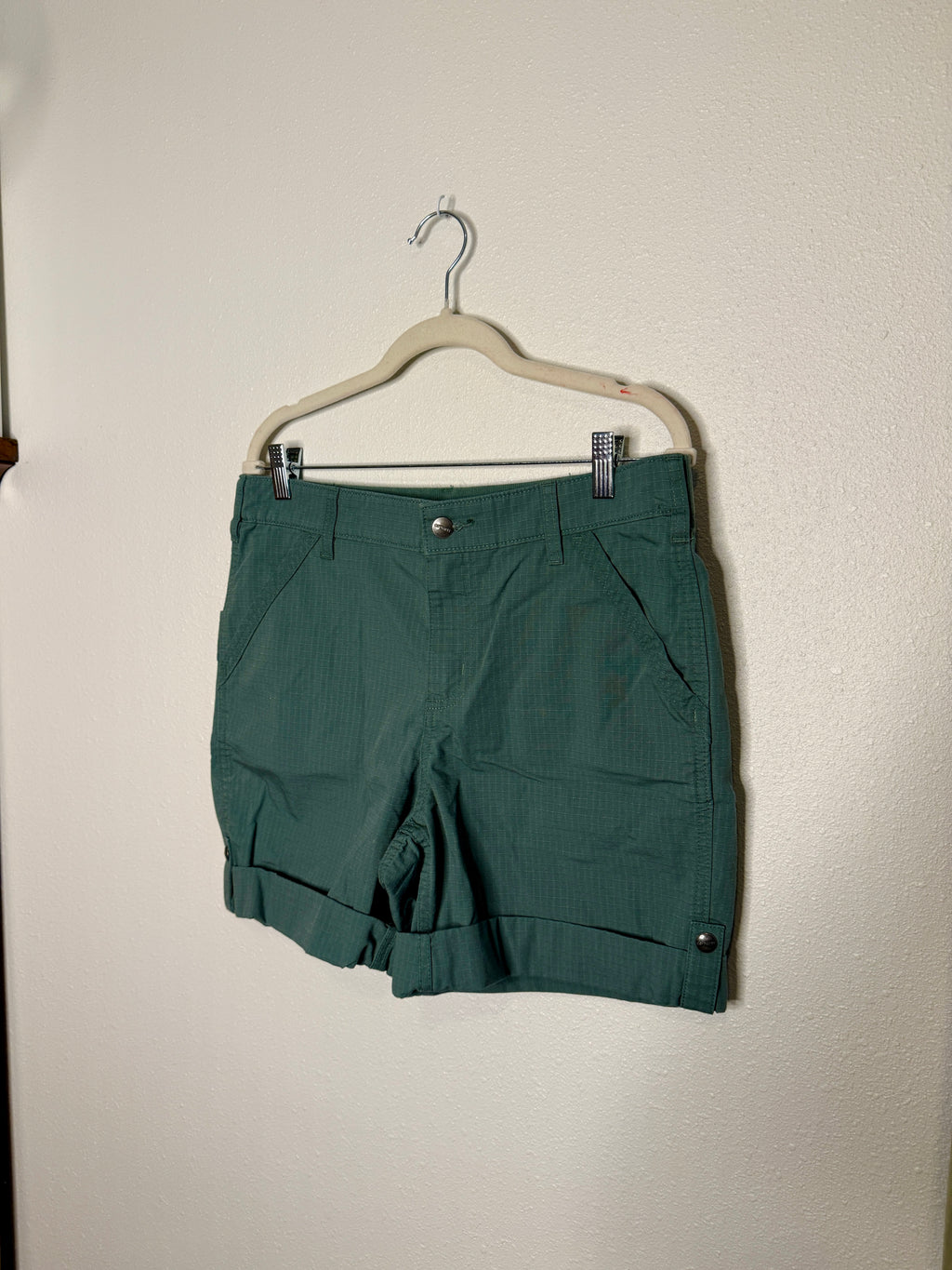 Green shorts on a hanger against a plain background