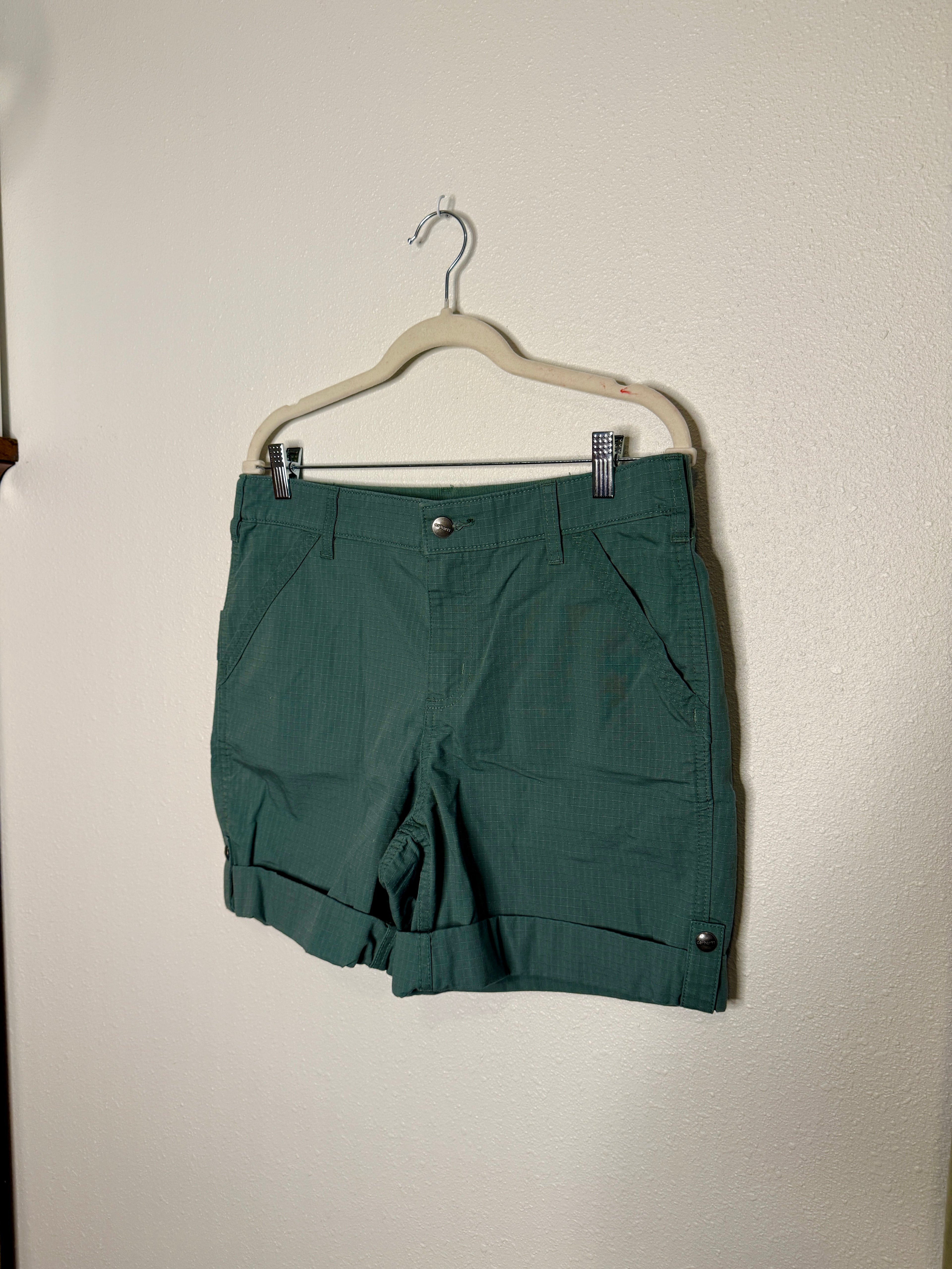 Green shorts on a hanger against a plain background