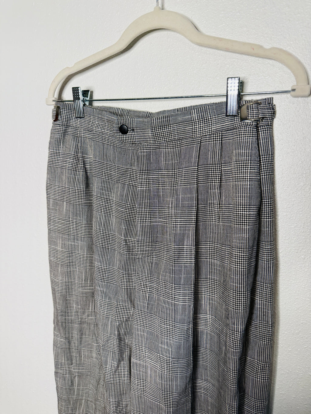 Plaid pants hanging on a white hanger against a white background