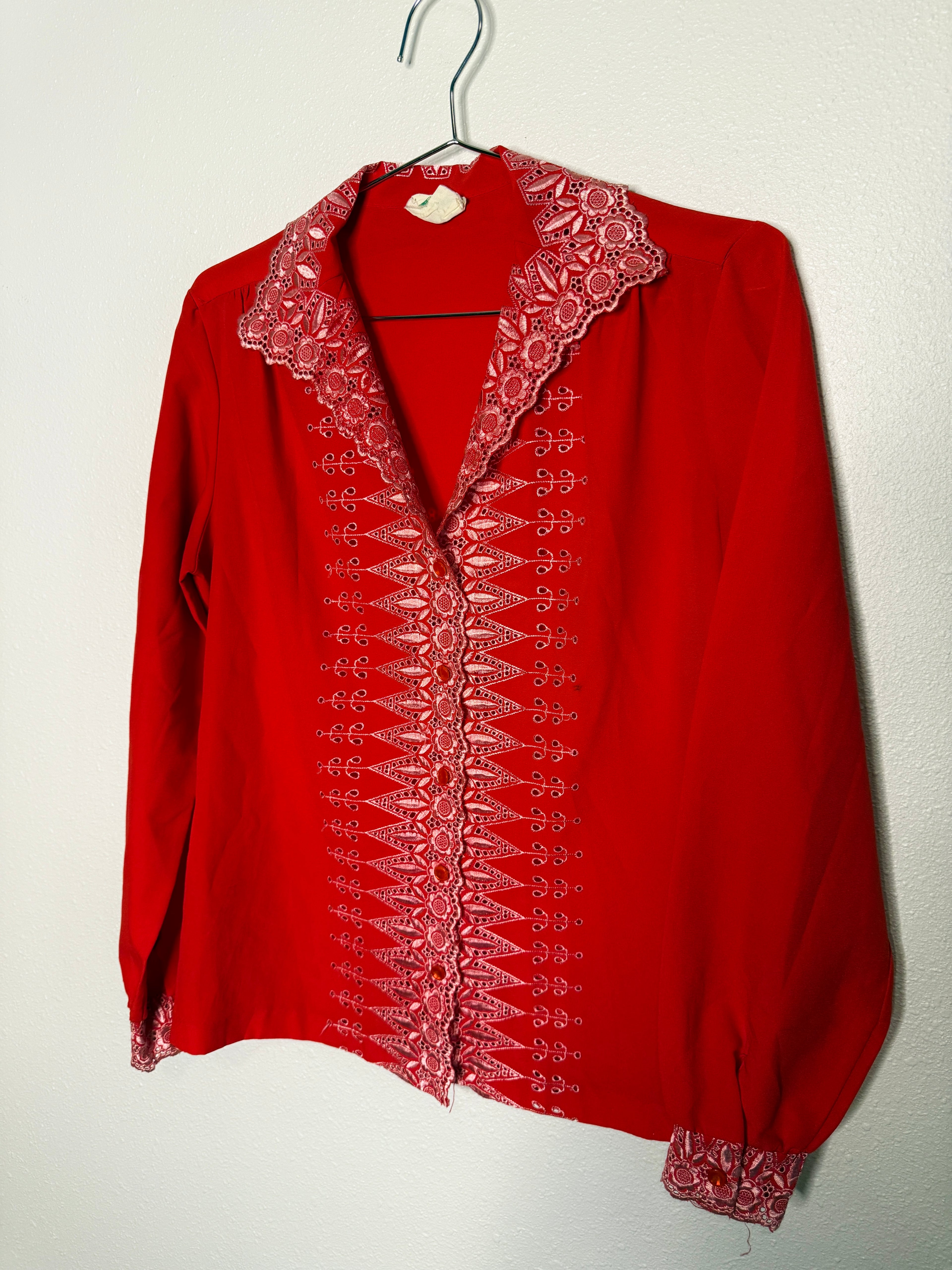 Red blouse with intricate white embroidery on a white background
